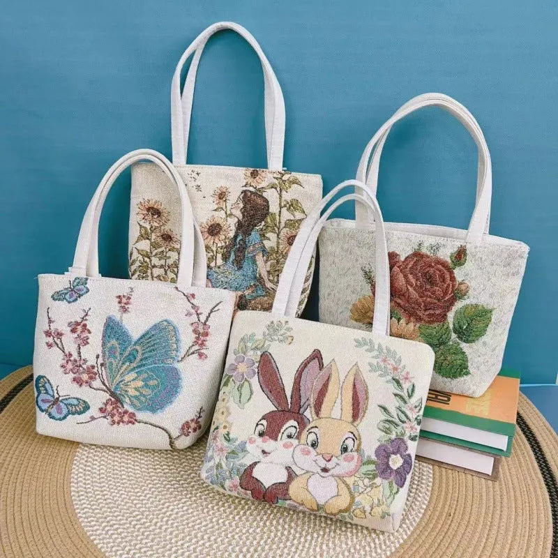 Double-sided embroidered canvas tote bag with gold wire trim, shown in a selection of seven colourways.