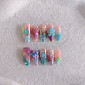 Handmade colourful embossed flower and butterfly nail art charms on a manicure set.