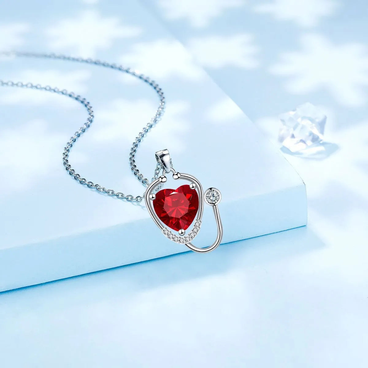 Red diamond women's necklace with stethoscope, wing, and cross pendant design on a copper chain.