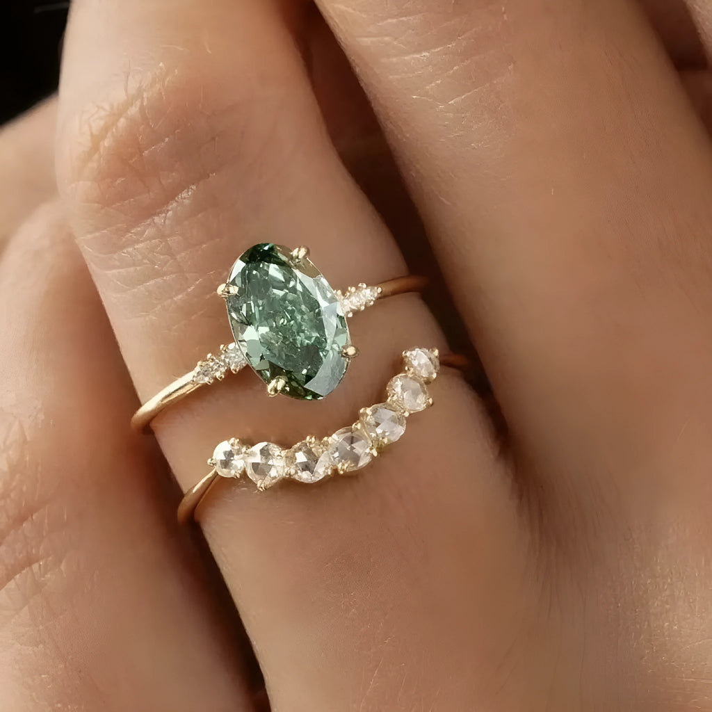 Gold S925 silver ring set with green moissanite stone, crown and geometric design, stacked on finger.