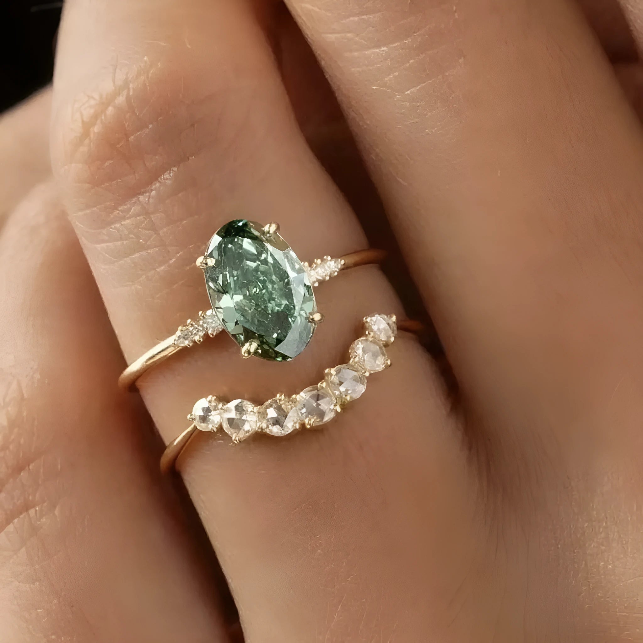 Gold S925 silver ring set with green moissanite stone, crown and geometric design, stacked on finger.