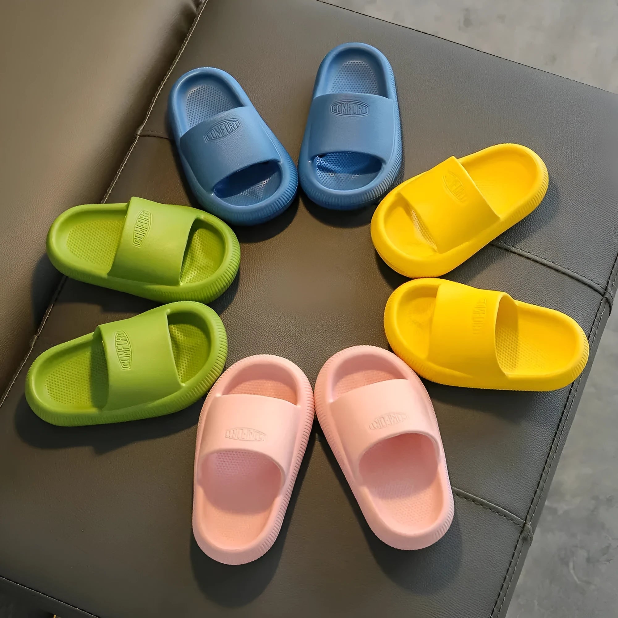 Bright coloured children's EVA slippers with textured sole, shown in blue, green, orange, pink, and yellow.