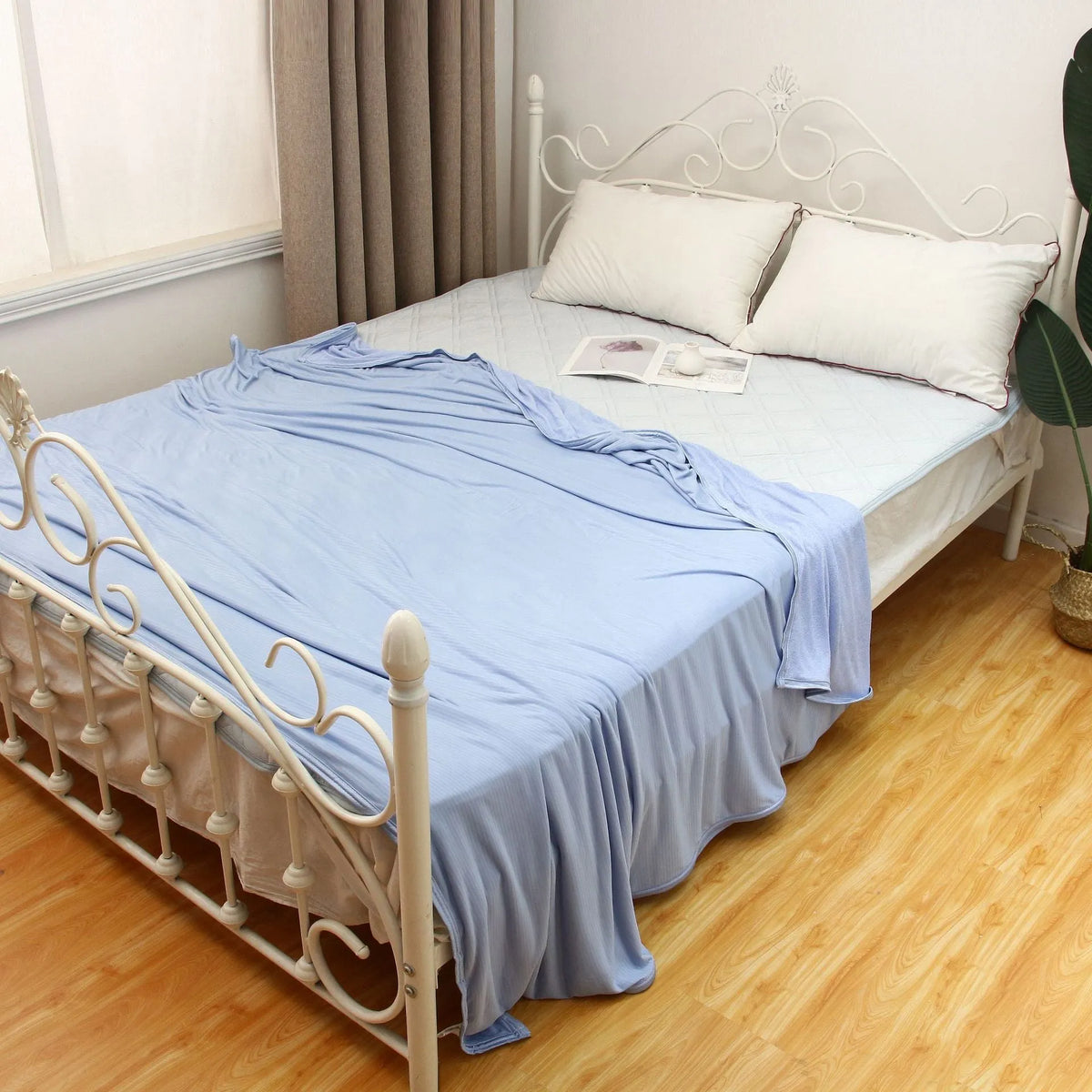 Cooling blanket in blue, grey, and pink colours on a bed, showing the polyester weave and Q-Max cooling fiber technology