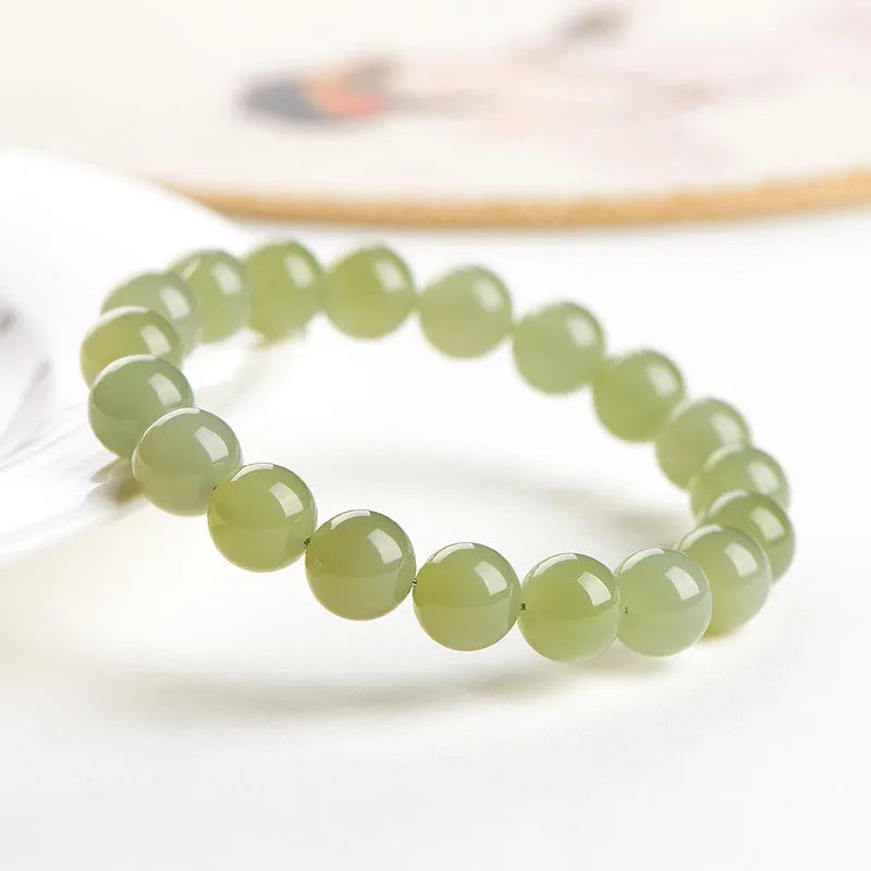 Polished Hetian jade ball bracelet on a wrist, showing spherical beads in a clear, ice-like colour.