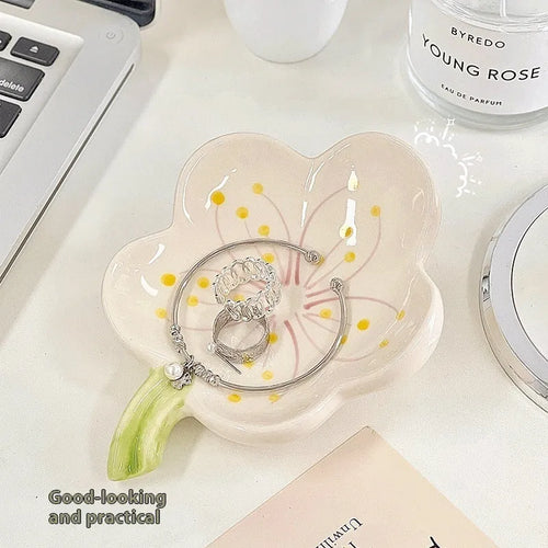 White and pink porcelain shell-shaped tray with integrated yellow LED night light on a wooden table.