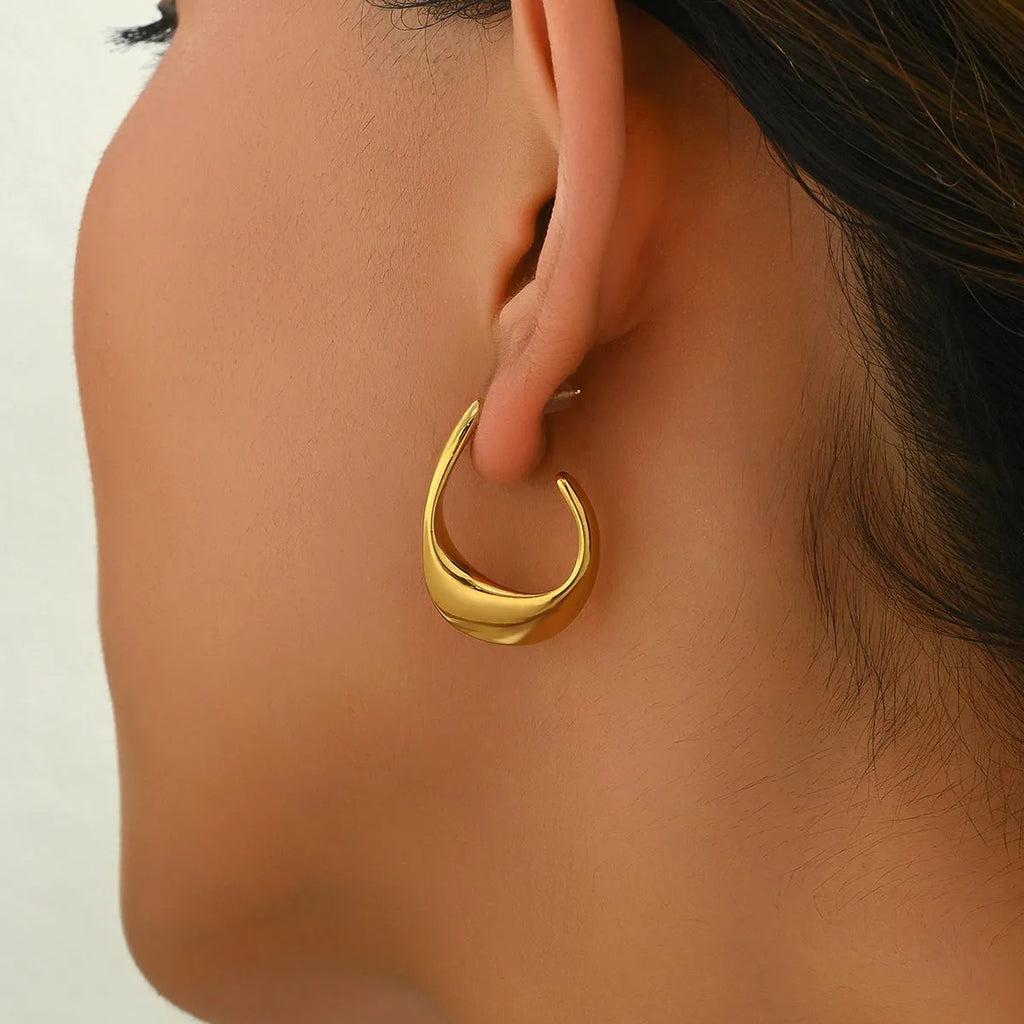 Geometric gold earrings with ring shape on stainless steel post-back closure against white background