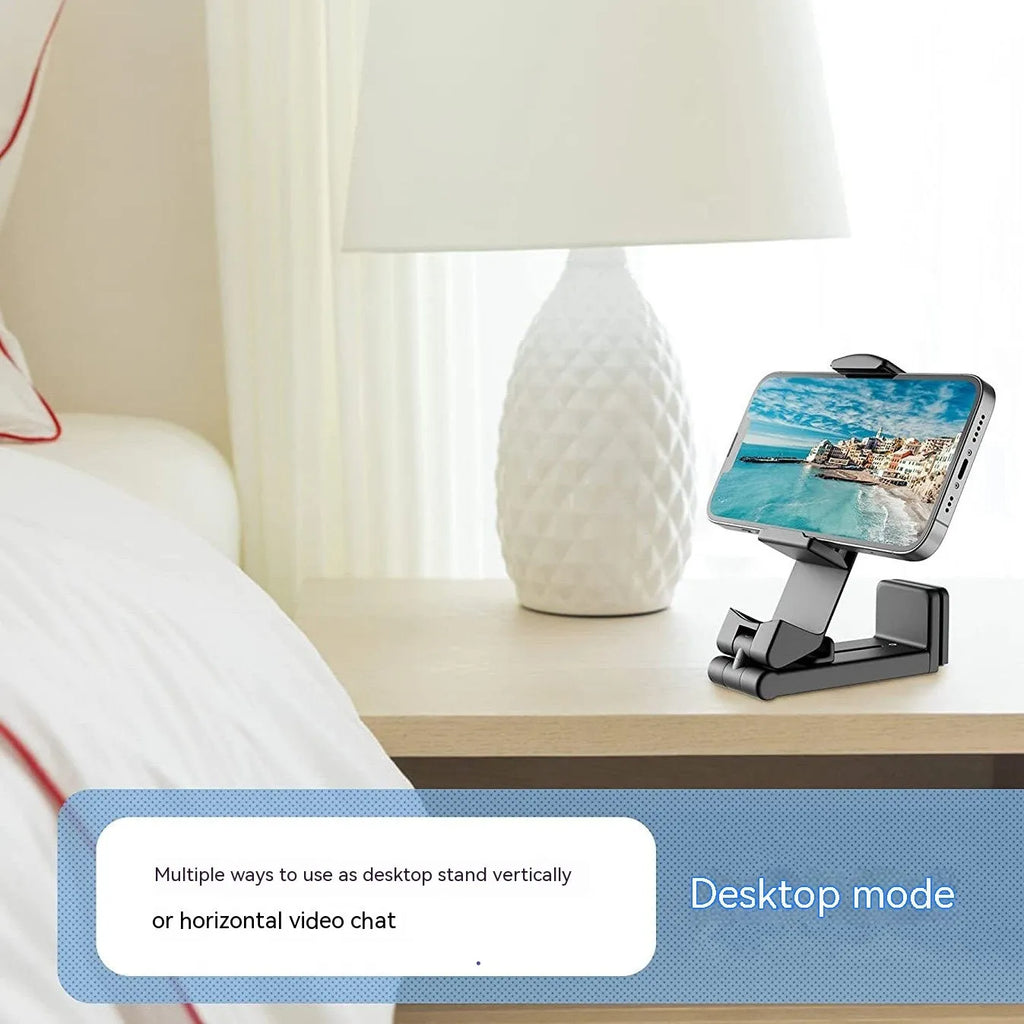 Black foldable rotating universal phone holder made of ABS plastic on a table.