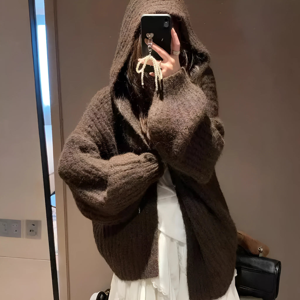 Woman wearing a thick dark grey hooded zip-up cardigan, loose fit.