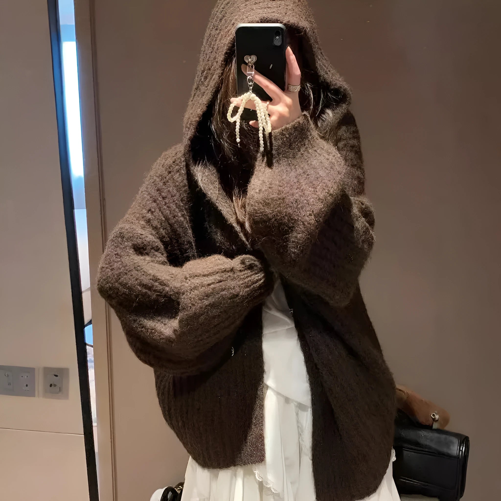 Woman wearing a thick dark grey hooded zip-up cardigan, loose fit.