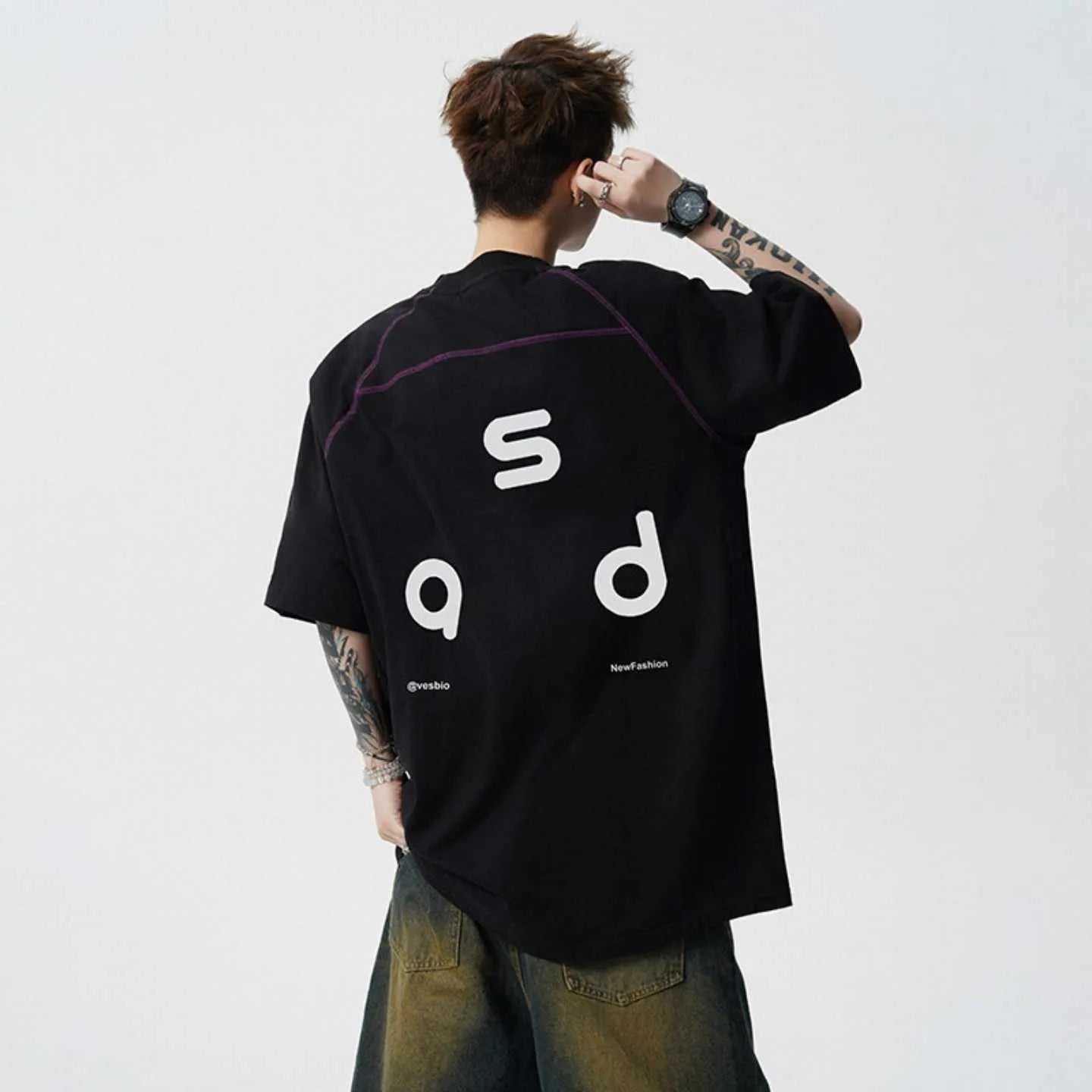 Man wearing a loose-fitting black cotton T-shirt with a white letter print on the chest.