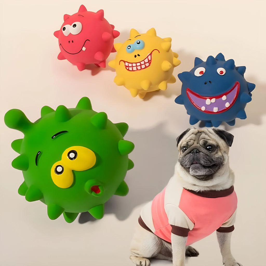 Set of four colourful latex squeaky dog balls with cute faces on a textured surface.