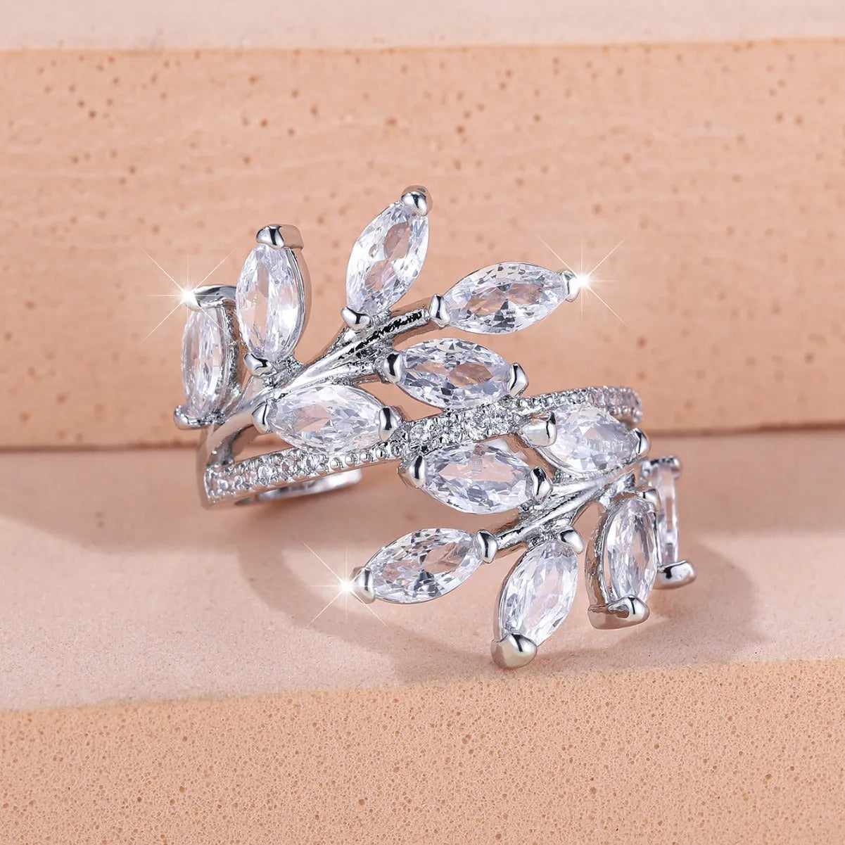 Adjustable copper leaf fashion ring with a central zircon stone on a model's hand, showing rose gold and platinum colour variants.