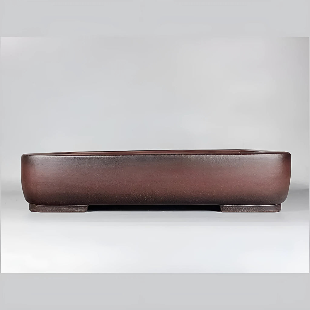 Large rectangular handmade antique purple clay flower pot on a table.
