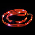 Luminous fluorescent PVC dog leash in orange, shown with hand holding loop.