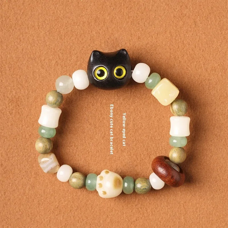Hand-woven beaded bracelet with bodhi, jade, and ebony beads featuring a cartoon cat's paw charm.