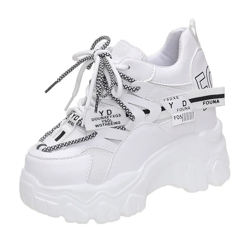 Women's white and black platform sports shoes with cross strap and rubber sole.