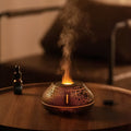 White round desktop aroma diffuser humidifier with colourful LED flame effect light on.