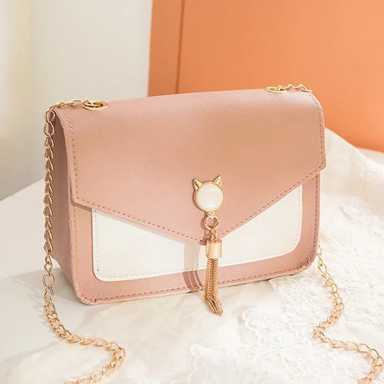 Small square PU leather messenger bag with cat tassel decoration and chain strap on a white background