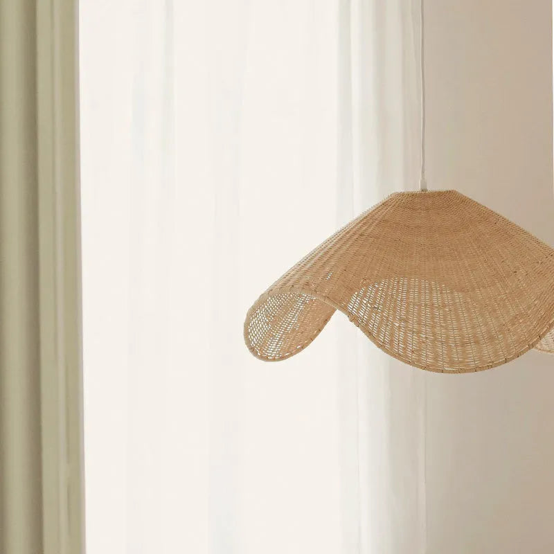 Handmade bamboo and straw rattan chandelier ceiling light with warm LED illumination in a rustic setting.