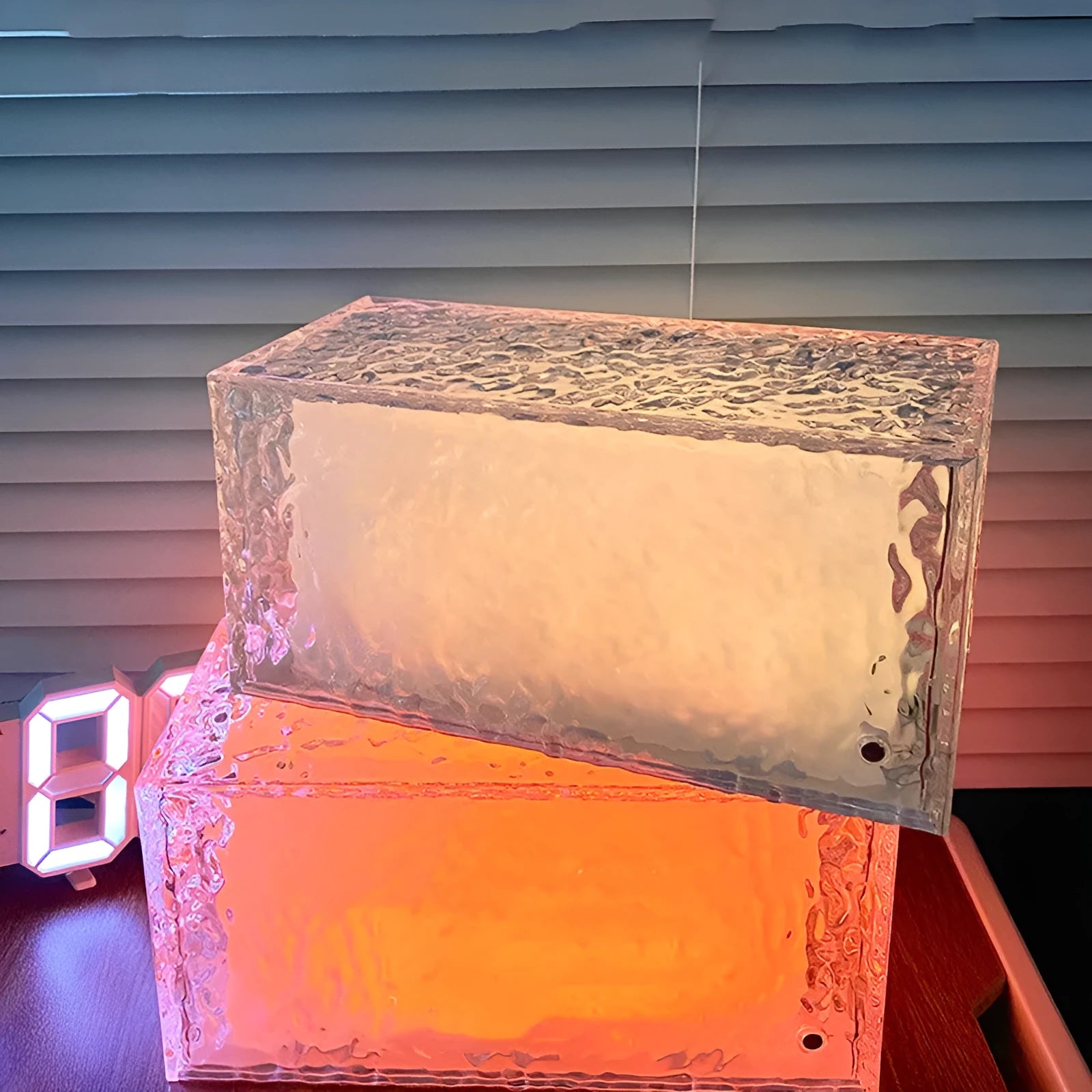 Clear acrylic geometric ice cube shaped night lamp glowing with soft blue LED light on a dark surface.
