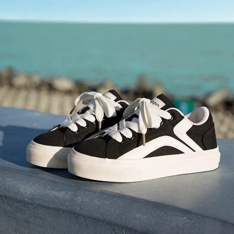 Women's low-top vulcanised board shoes in a black and white colourway with round toe and lace-up front.