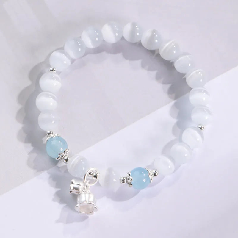 Close-up of a women's opal cat's eye stone beaded bracelet with diamond-shaped beads on a wrist.