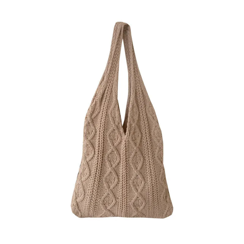 Women's white hollow knitted crochet tote bag with double shoulder straps, shown on a table.