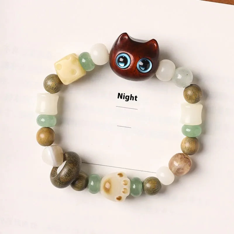 Hand-woven beaded bracelet with bodhi, jade, and ebony beads featuring a cartoon cat's paw charm.