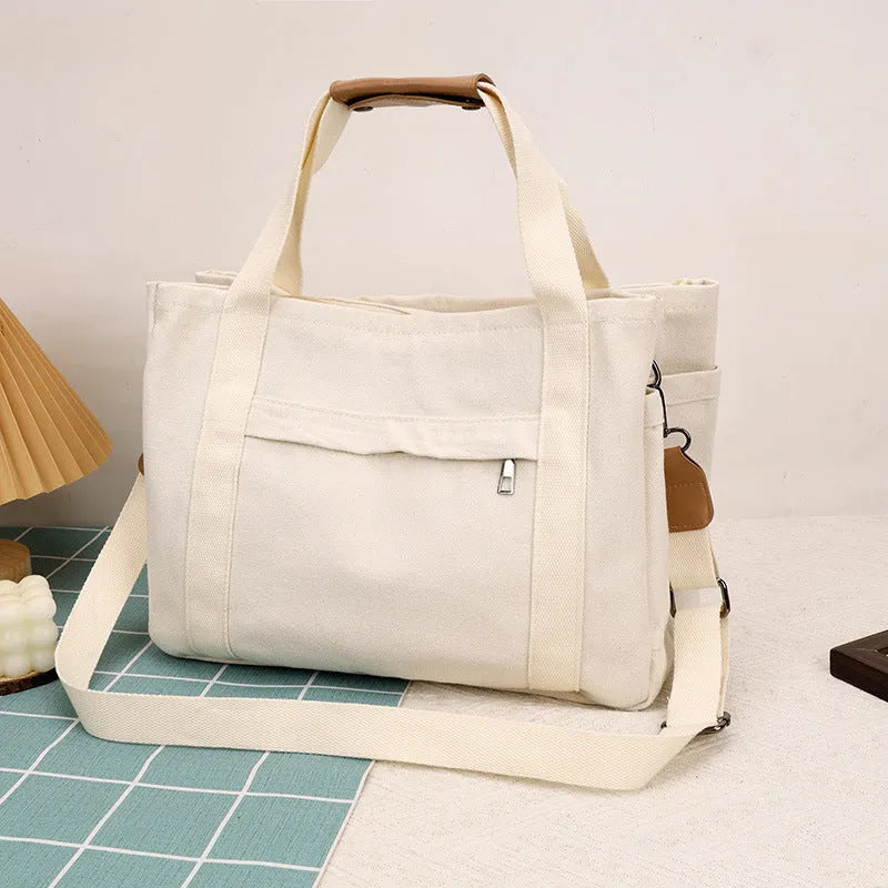 Canvas tote bag with internal organisation pockets for phone, documents, laptop, and camera in horizontal square shape