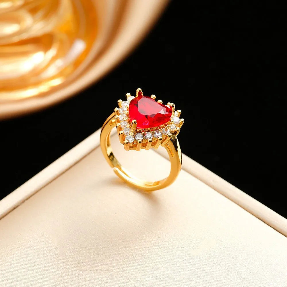 Gold-red heart pendant necklace with gemstone inlay, matching ear studs, and ring on a titanium steel water wave chain.