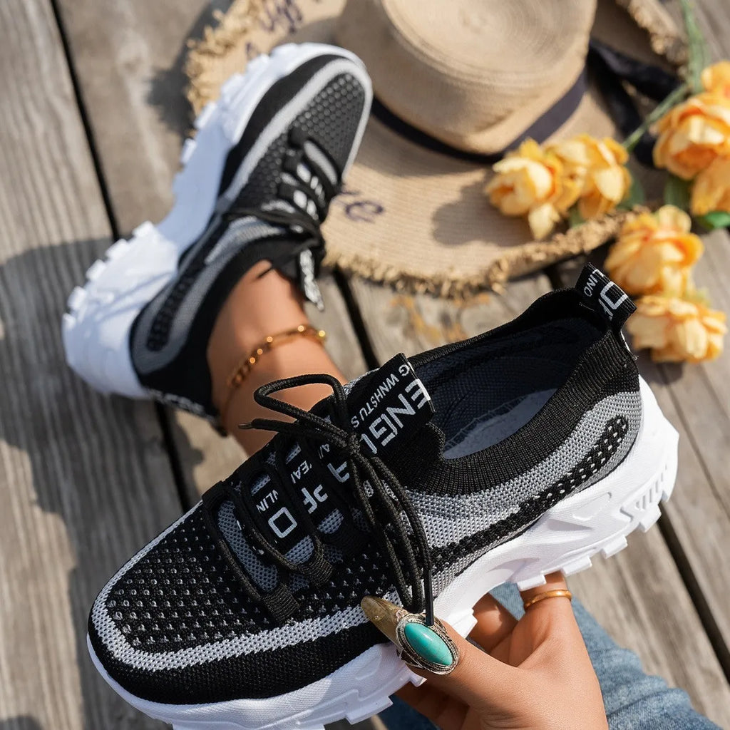 Women's Flyknit mesh lace-up sneakers in grey and white colour combination on a flat rubber sole.