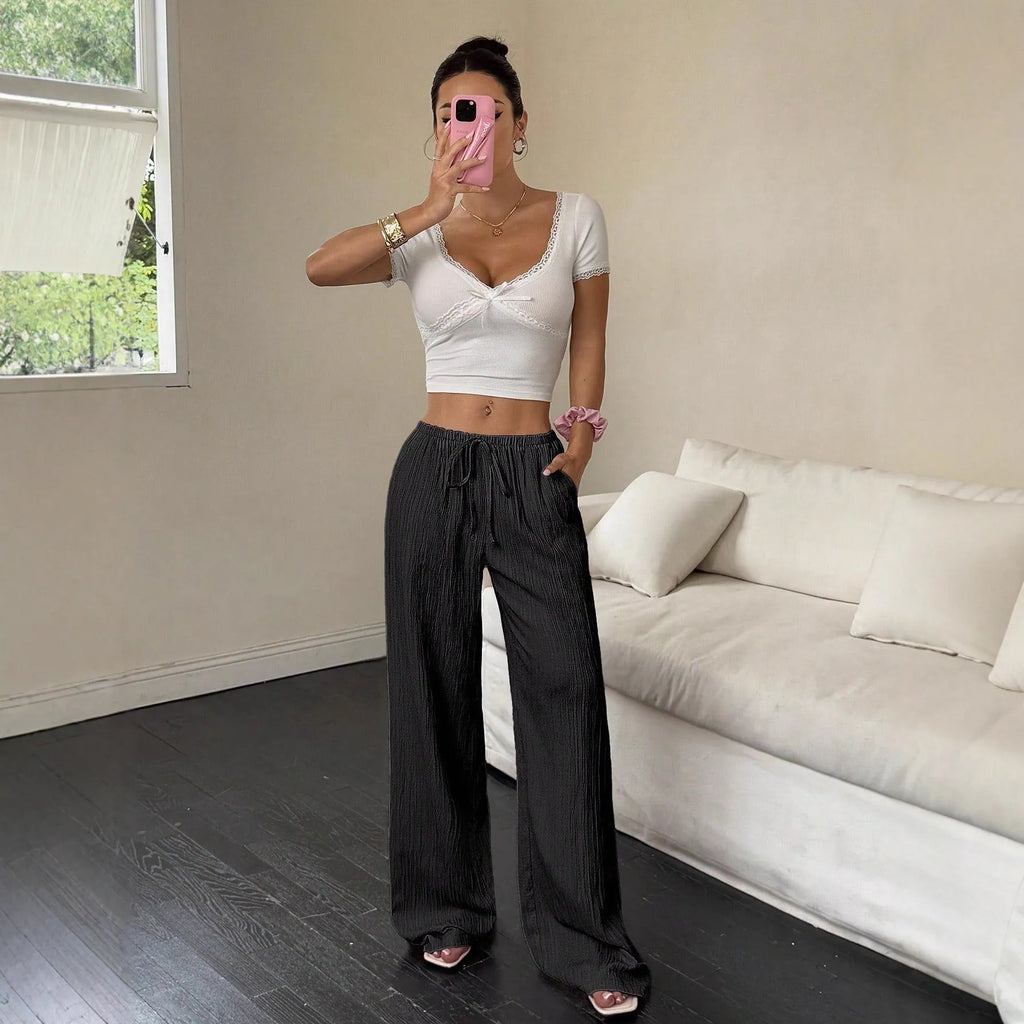 Women's black wide-leg trousers with a front lace-up waist detail, shown in a casual standing pose.