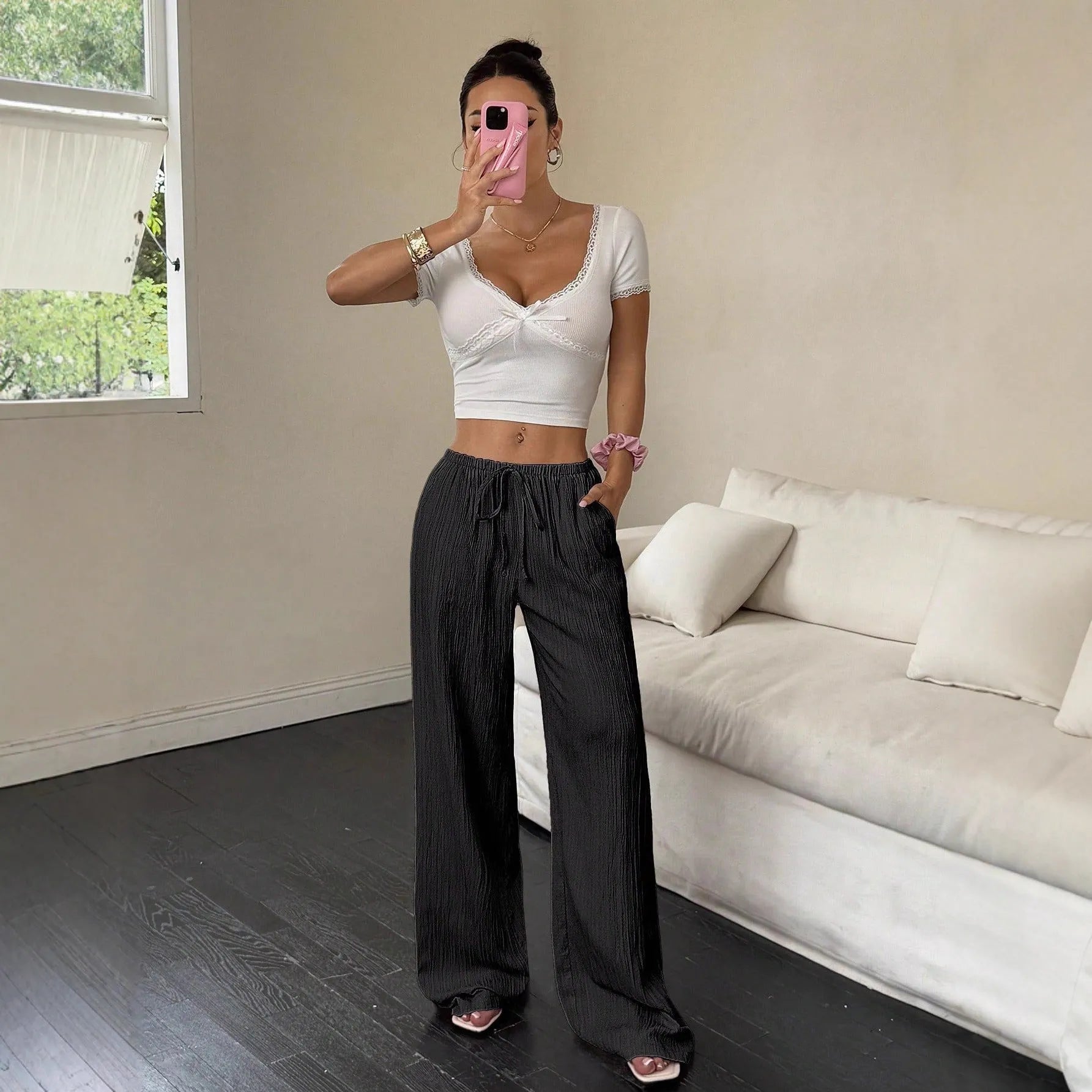Women's black wide-leg trousers with a front lace-up waist detail, shown in a casual standing pose.