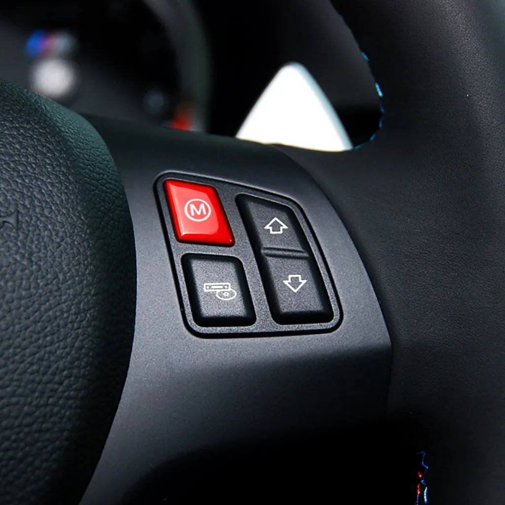 Pair of red and blue BMW M1 and M2 steering wheel mode buttons on a white background.
