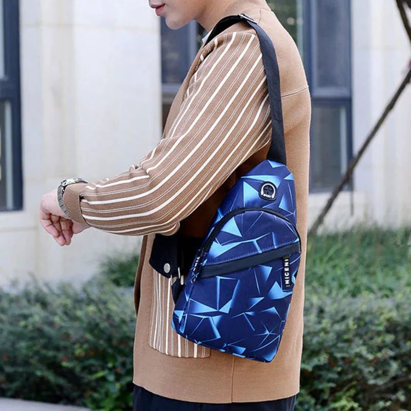 Men's blue print sling chest crossbody bag showing earphone hole and zipper pocket.