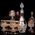 Six yellow crystal glass whiskey glasses with golden accents on a table