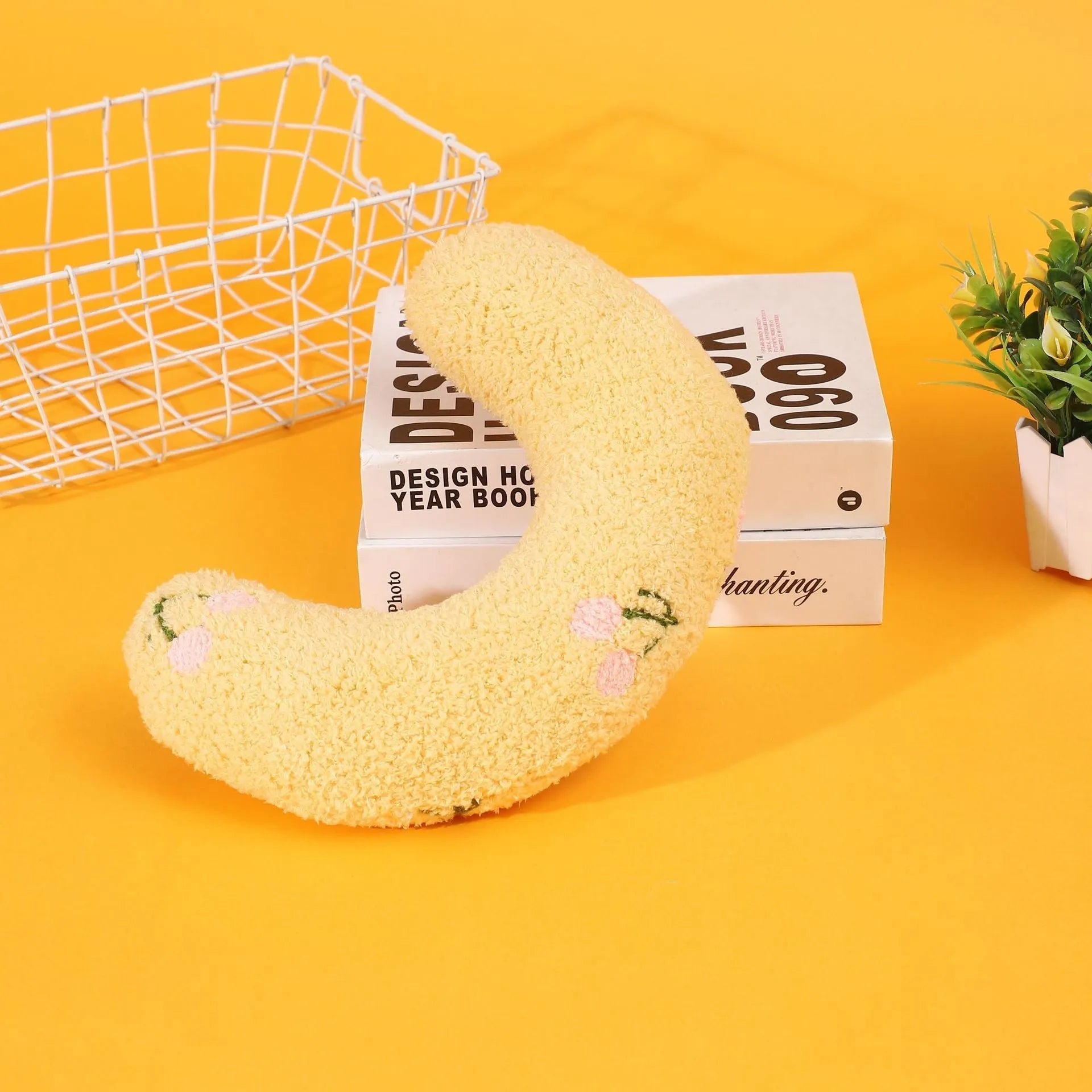 Yellow half-moon shaped cloth pillow with cartoon design for cats and dogs to sleep on.