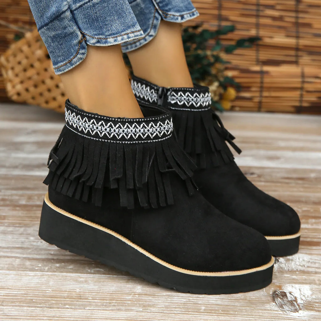 Women's black wedge bootie with suede upper, thick rubber sole, side zipper, and tassel detail.