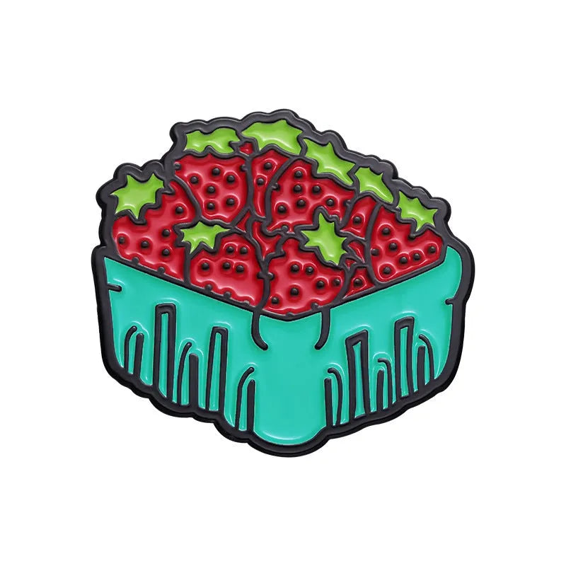 Close-up of a colourful cartoon strawberry metal brooch with a safety-pin clasp, on a denim jacket pocket.