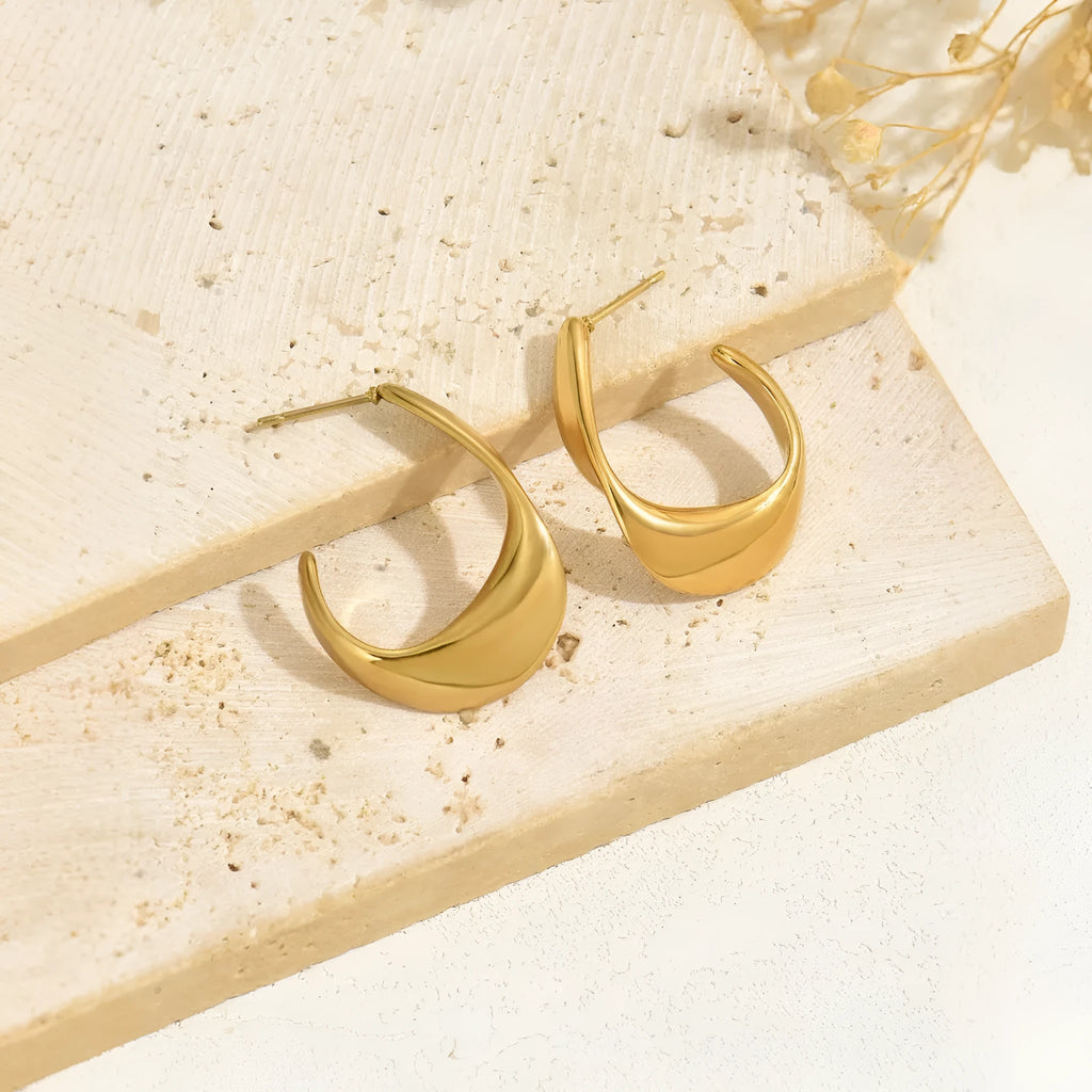 Geometric gold earrings with ring shape on stainless steel post-back closure against white background