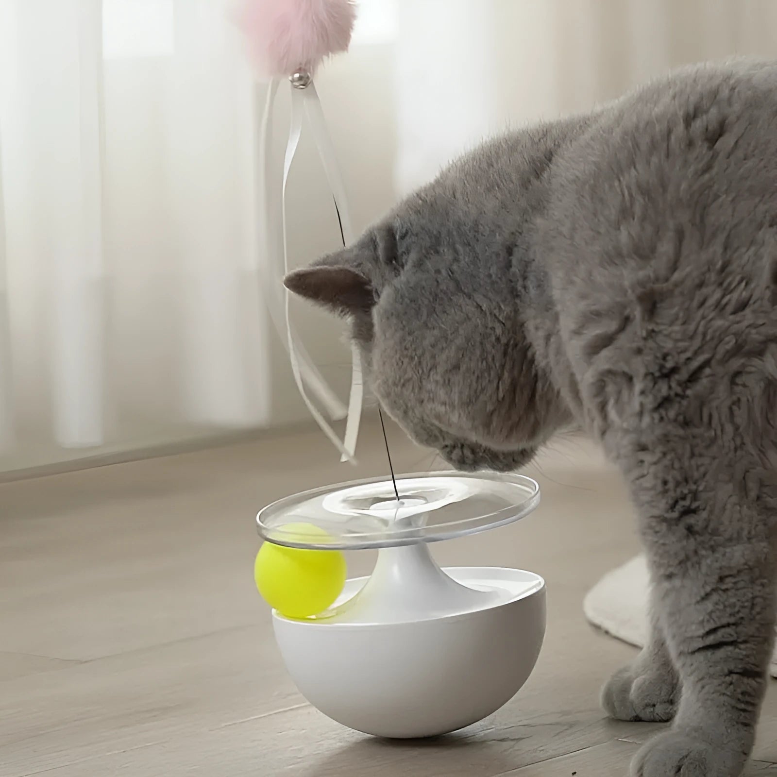 White tumbler cat toy with self-congratulating stick on a light floor