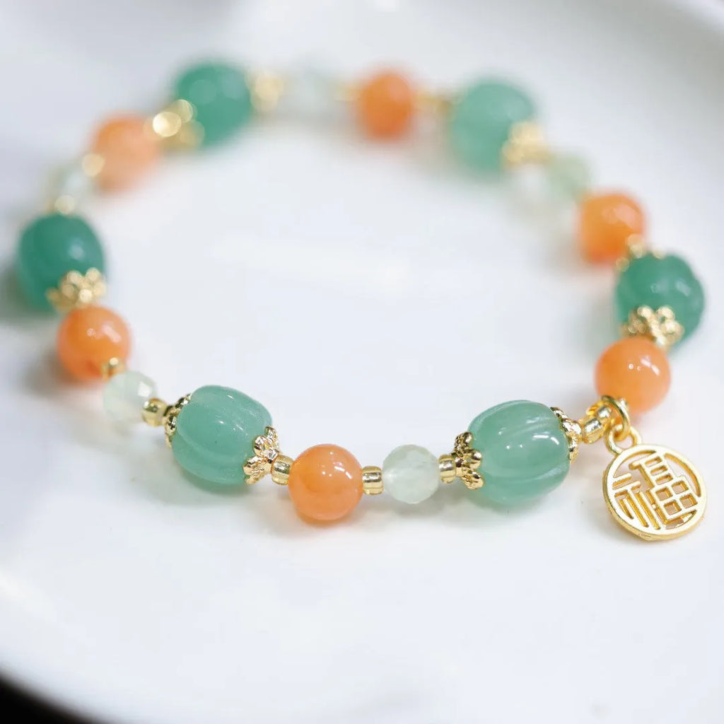 Close-up of a jade and prehnite Chinese-style pumpkin bead bracelet on a wrist.