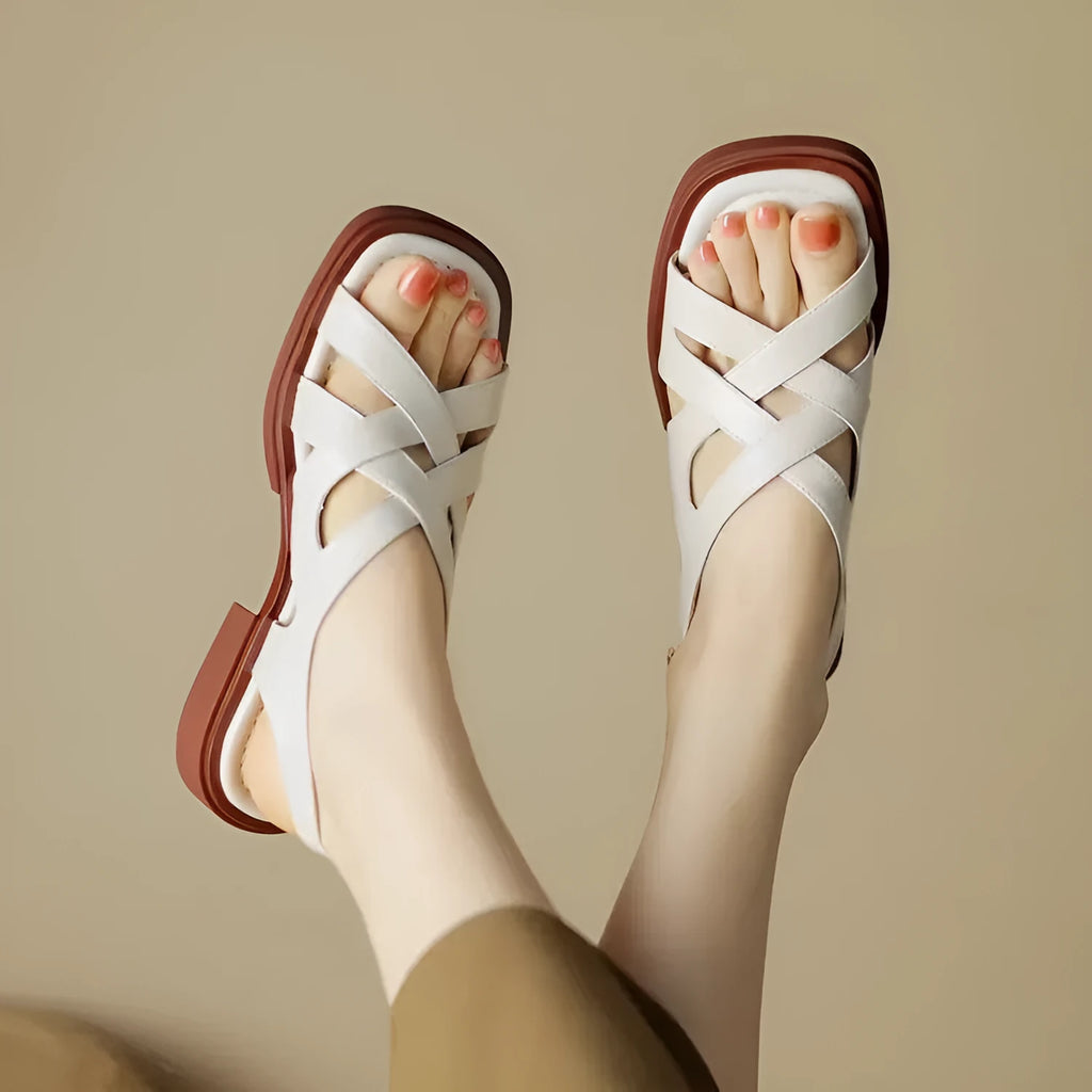 Women's glossy patent leather square toe sandals with a cross-strap design in black.