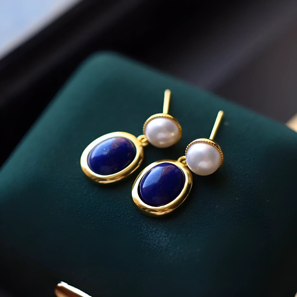 A pair of simple drop earrings featuring a blue lapis lazuli pearl set in patterned sterling silver.