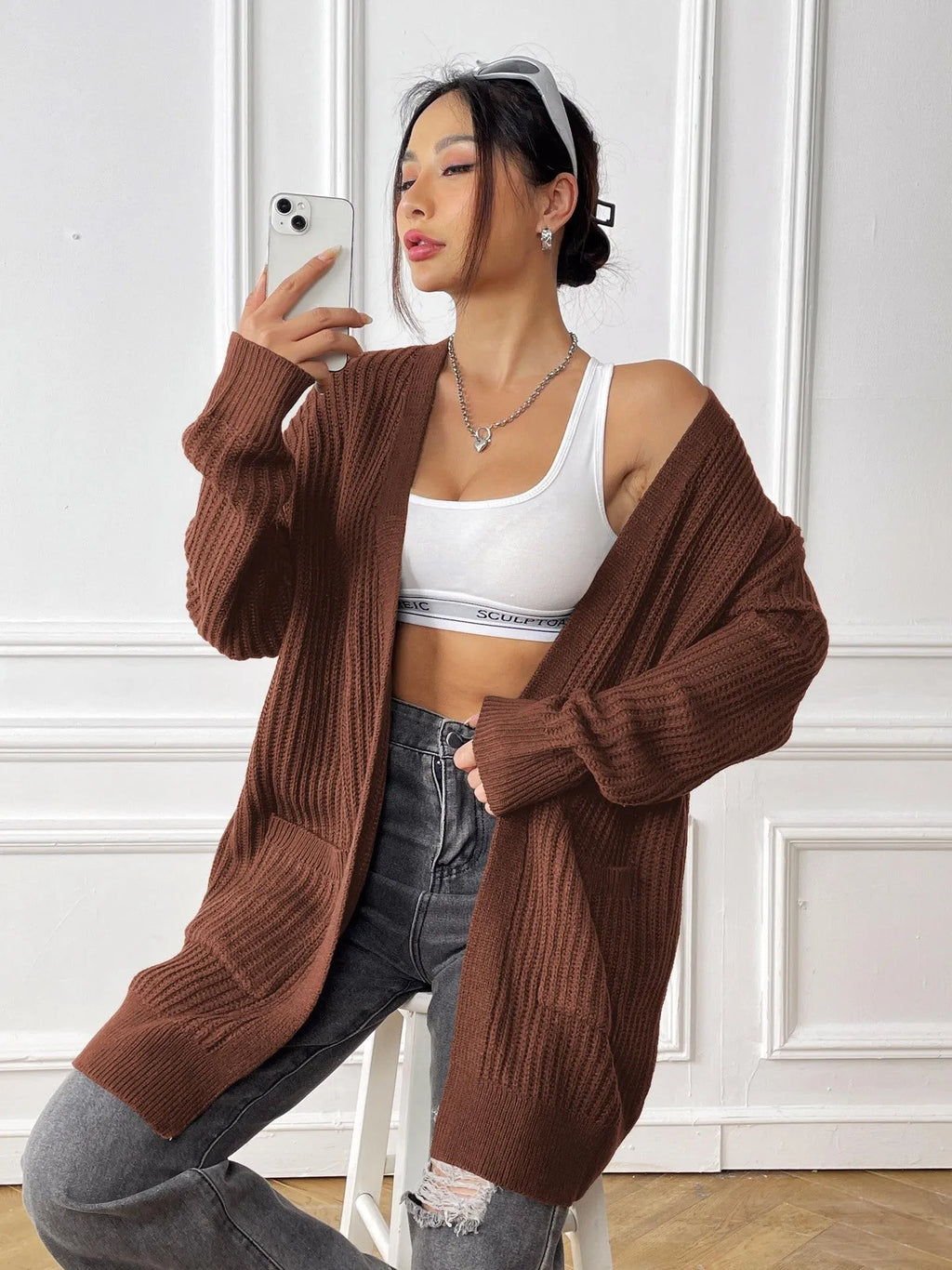 Women's dark green double pocket casual cardigan sweater laid flat.