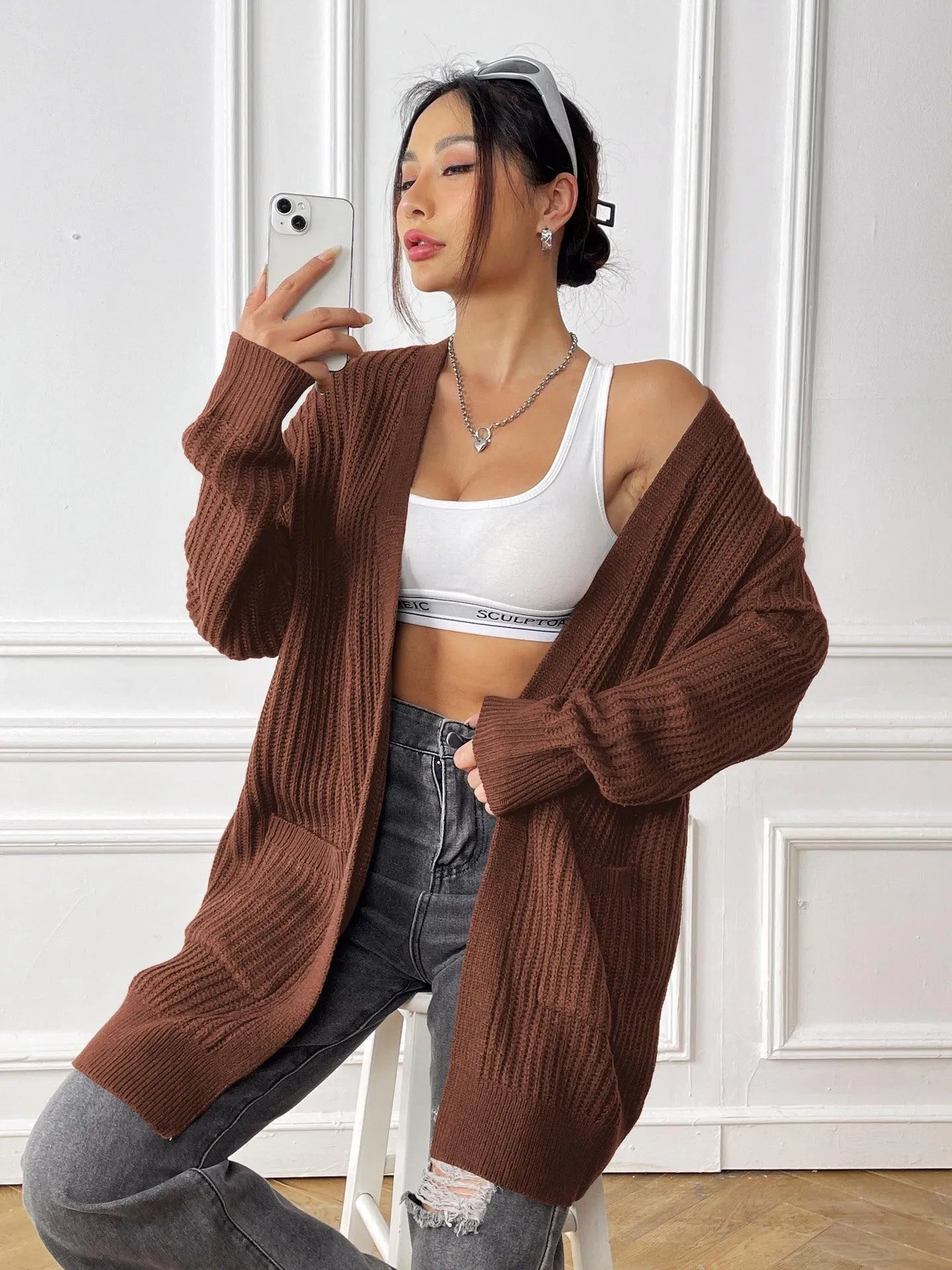 Women's dark green double pocket casual cardigan sweater laid flat.