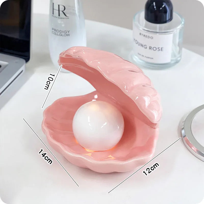 White and pink porcelain shell-shaped tray with integrated yellow LED night light on a wooden table.