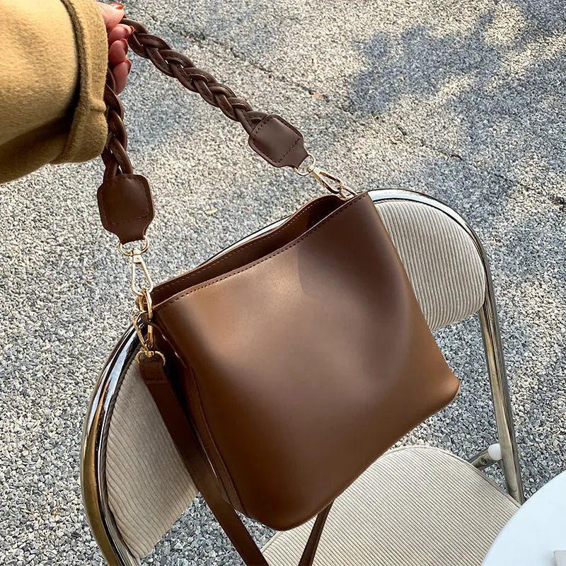 Woven pattern PU leather crossbody bucket bag worn underarm, shown in khaki colour.