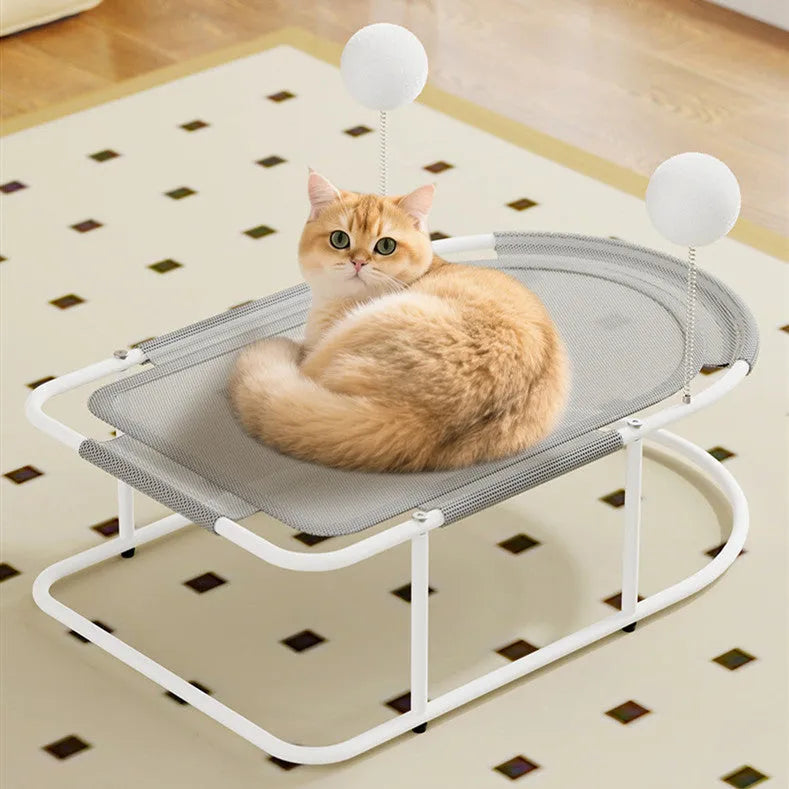 Grey fabric cat kennel with open sides and a round, removable floor pad on a carpet.