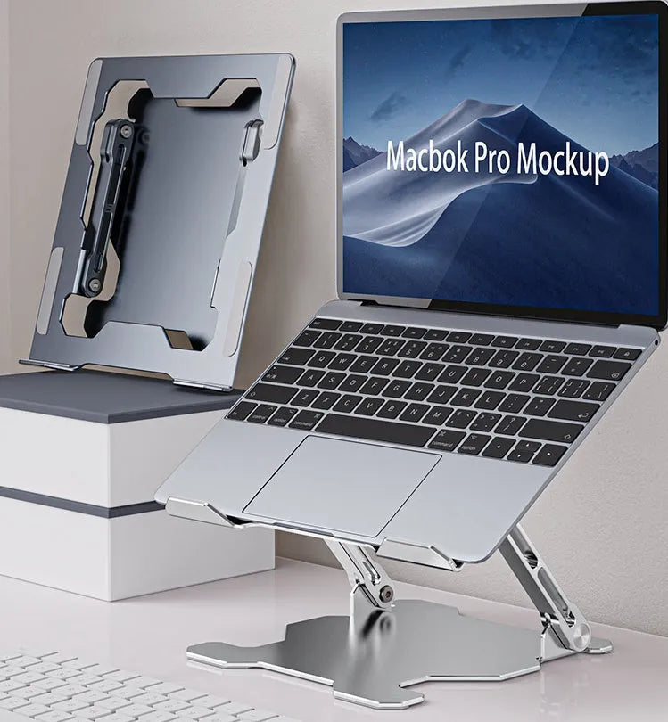 Grey aluminium laptop stand in a folded position next to an open laptop, showing its adjustable angle and hollow design.